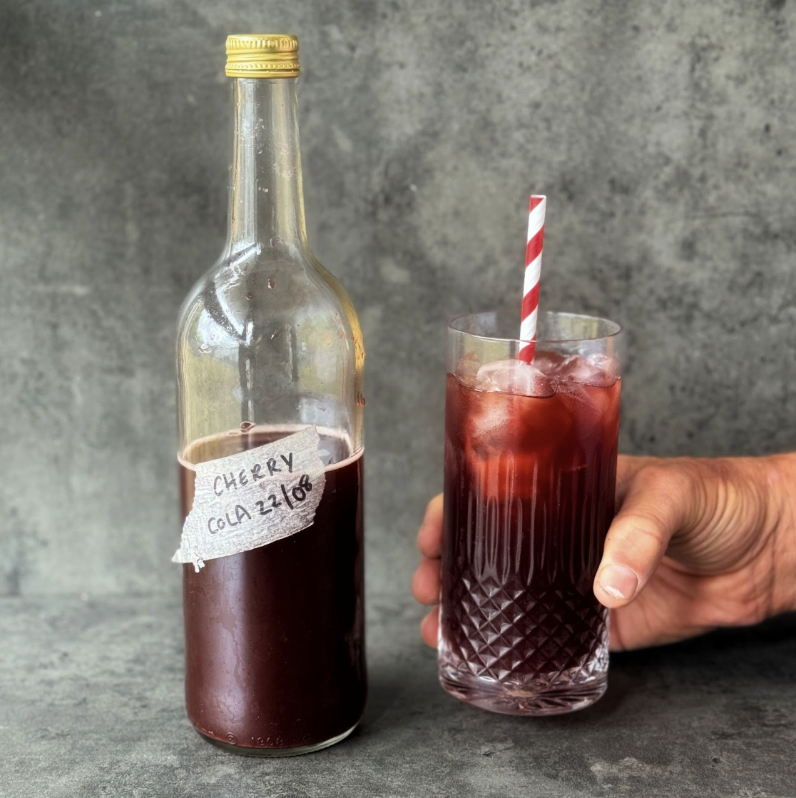 a photo of a bottle and a glass of homemade naturally fermented cherry cola