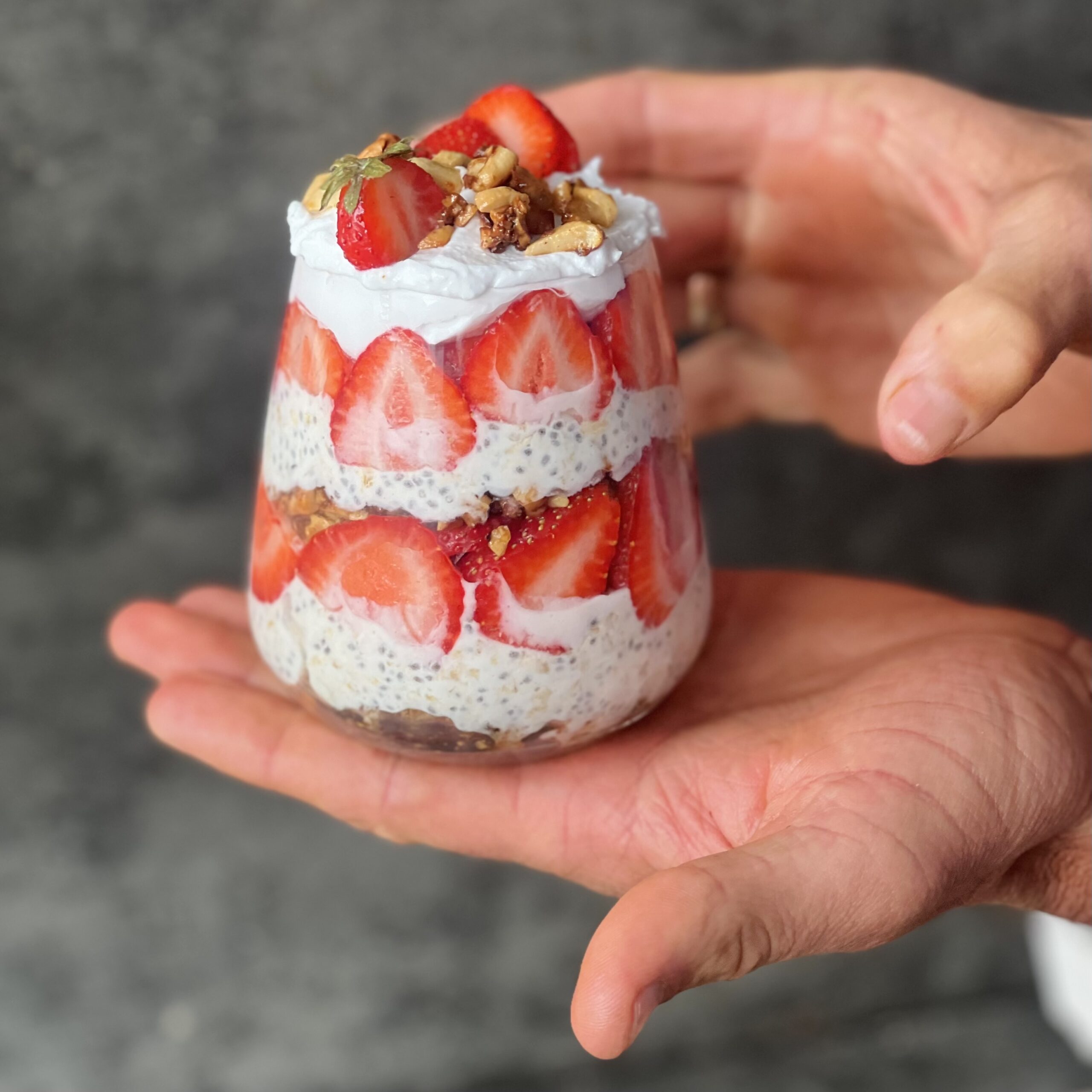 A photo of a clear glass with layers of Strawberry Shortcake Overnight Oats