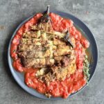 a photo of Aubergine Schnitzel on a bed of tomato sauce