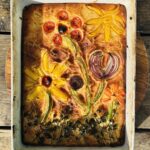 a photo of focaccia pizza with flower design toppings